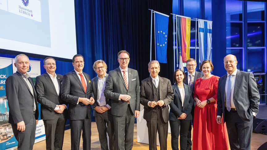 Eine Gruppe von zehn Menschen, die auf einer Bühne nebeneinander stehen. Zwei davon sind Frauen.